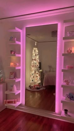 a white christmas tree sitting in the middle of a room with pink lights on it