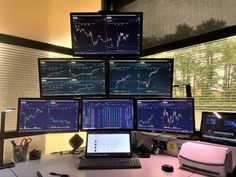 multiple computer monitors and laptops on a desk