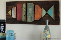 a wooden fish wall hanging on a wall next to vases and other decorative items