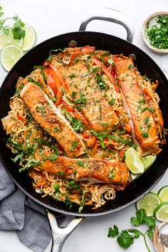 a skillet filled with fish and noodles, garnished with cilantro