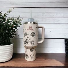 a coffee cup sitting on top of a wooden table next to a potted plant