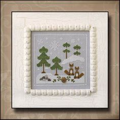 a cross - stitch picture frame with an animal scene in the middle and trees around it