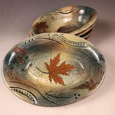 three ceramic plates with leaves painted on them