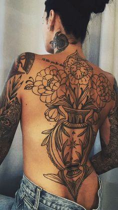 the back of a woman's body with tattoos on her upper and lower half