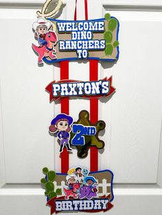 a bunch of signs hanging from the side of a door that says, welcome dino ranchers to photon's 2nd birthday