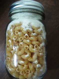 a jar filled with macaroni and cheese on top of a wooden table