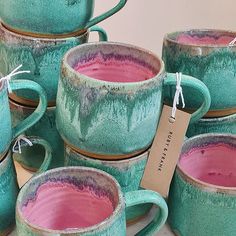 a pile of pink and green coffee mugs sitting next to each other on a table