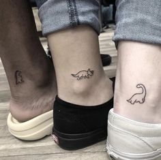 two people with matching tattoos on their feet are standing next to each other and one has a dinosaur tattoo on the ankle