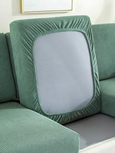 a green couch sitting next to a white wall