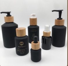 several black bottles with wooden caps are lined up against a white background and one is empty