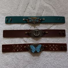 three different colored belts with butterfly buckles on the sides and one is brown, blue, and green