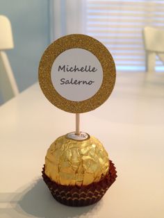 a cupcake with a name tag on it sitting on top of a white table