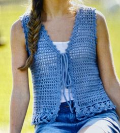 a woman sitting on a bench wearing a blue crochet vest