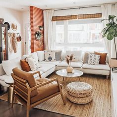 a living room with white couches and pillows on top of the rug in front of a large window