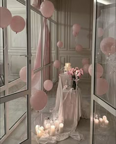 a table with pink balloons and candles in front of a mirror on the floor next to it