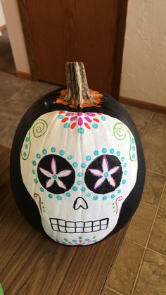 a painted pumpkin with a skull on it's face sitting on the floor in front of a door