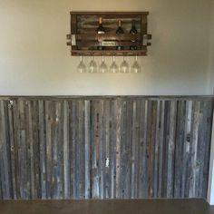 a wooden wall with wine glasses hanging from it's sides and bottles on the top shelf