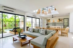 a living room filled with furniture and lots of windows next to a dining room table