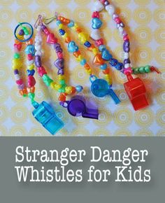 several bracelets with beads and charms hanging from them on a tablecloth that says, strangeer danger whistles for kids