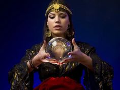 a woman holding a crystal ball in her hands while wearing an elaborate headdress