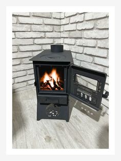 a black stove sitting on top of a wooden floor next to a brick wall with a fire in it