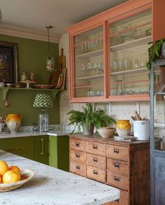 a bowl of oranges sitting on top of a counter next to a glass cabinet