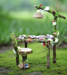 a miniature garden bench and table with flowers on the seat is shown in front of green grass