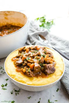 a white bowl filled with food next to a pot of stew