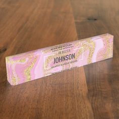 a pink and gold bar of soap sitting on top of a wooden table