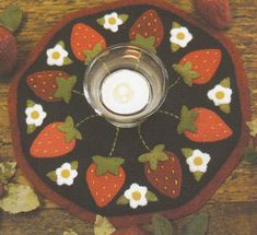 a candle holder with strawberries and daisies on it