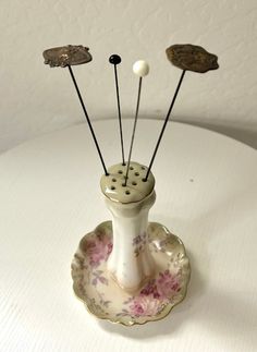 three pins in a vase on a white table