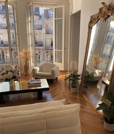 a living room filled with white furniture and lots of windows next to a wooden floor