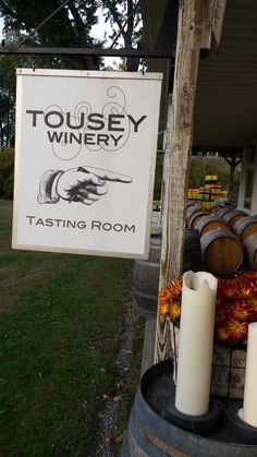 a sign that says tousey winery tasting room next to some wine casks