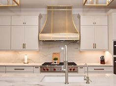 a kitchen with marble counter tops and stainless steel range hood over the stove, surrounded by white cabinets