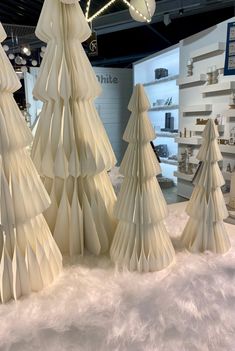 three paper christmas trees on display in a store with white fluffy fur around the edges