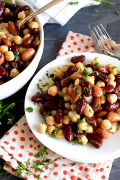 two white bowls filled with beans and garbanzos on top of a table