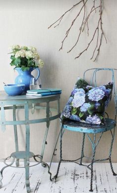 a blue chair sitting next to a table with flowers on it