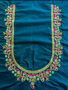 an embroidered blue cloth with gold and green designs on it's edges, in the shape of a letter u