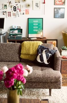 a living room filled with furniture and flowers in a vase on the floor next to a couch