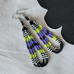 two pairs of beaded earrings sitting on top of a piece of white fabric next to a black and yellow object