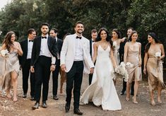 a group of people standing next to each other on a dirt road in front of trees