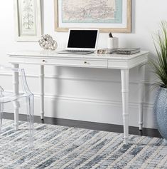 a laptop computer sitting on top of a white desk next to a blue vase filled with flowers