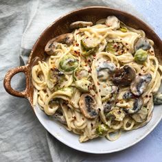 a bowl filled with pasta and mushrooms on top of a blue cloth covered tablecloth