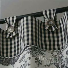 black and white checkered curtains with buttons on them are hanging from a metal rod