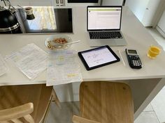 a laptop computer sitting on top of a white table next to a plate of food