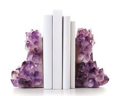 three books are stacked on top of each other with purple crystals in front of them