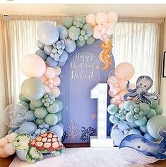 an ocean themed 1st birthday party with balloons and sea animals on the front, under a balloon arch