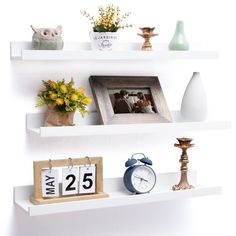 two white shelves with pictures, flowers and an alarm clock