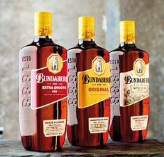 three bottles of rum sitting on top of a wooden table