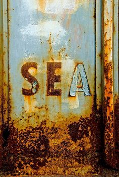 an old rusted metal door with the word sea painted on it